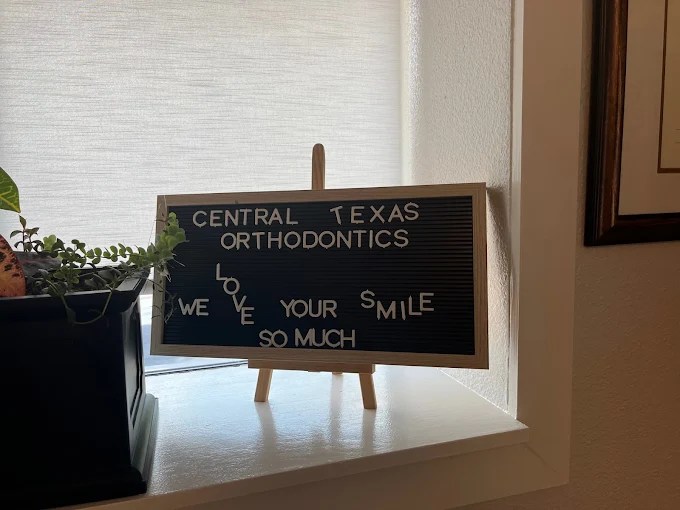 A small tabletop chalkboard with handwritten notes displayed on a wooden stand.