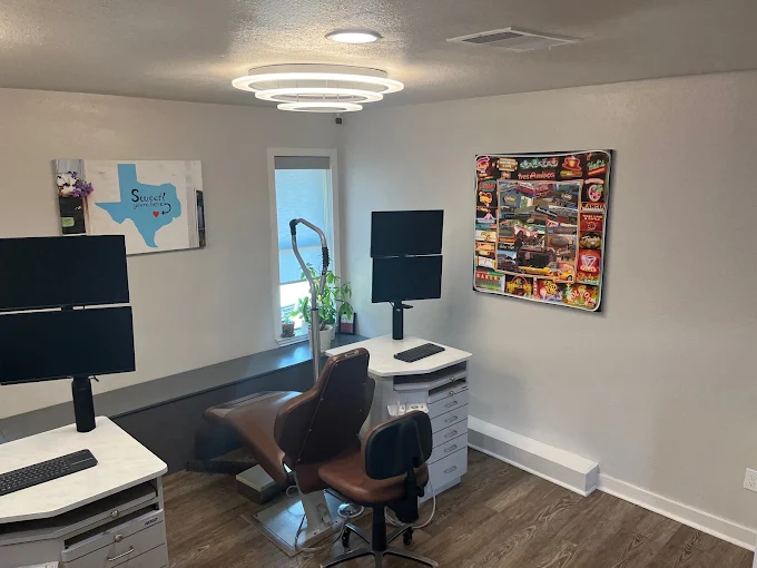 A private office space with a desk, two computer monitors, and decorative art on the walls.