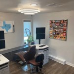 A private office space with a desk, two computer monitors, and decorative art on the walls.