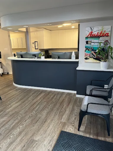 A clean, modern reception desk with a dark navy base and white countertop, featuring wood-look flooring and a bright interior.