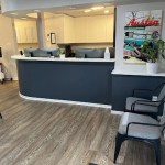 A clean, modern reception desk with a dark navy base and white countertop, featuring wood-look flooring and a bright interior.